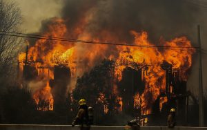 The photo shows firefighters in front of a house that is burning strongly
