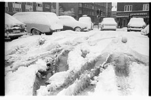 Mit Schnee bedeckte Autos stehen auf einem zugeschneiten Parkplatz